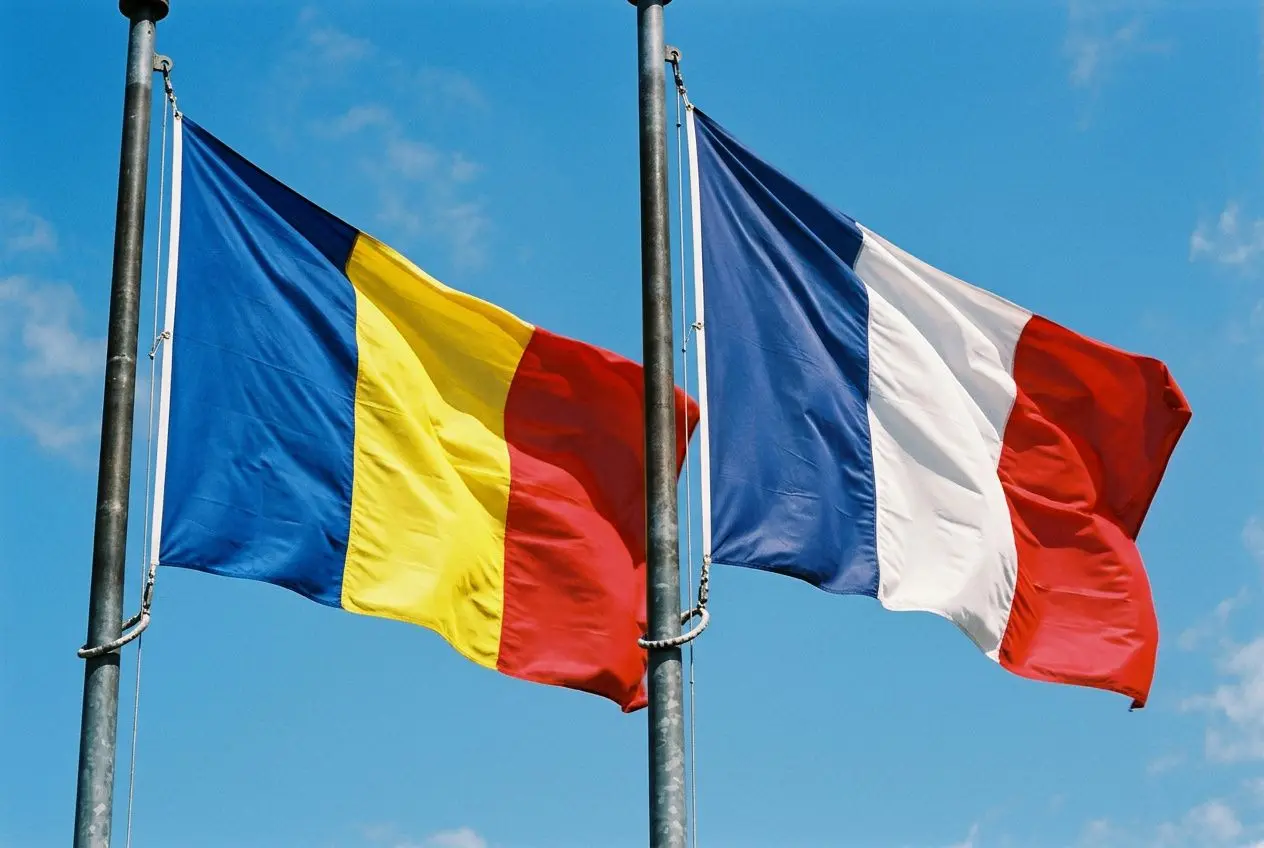 Drapeaux de la Roumanie et de la France hissés côte à côte contre le ciel bleu, symboles de coopération européenne.